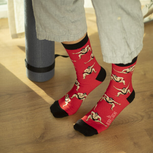 Chaussettes originales montrant des sumos sur fond rouge vif