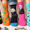 Pieds alignés portant des chaussettes fantaisie Altersocks : aliens, cactus, Freud, pizza et planètes
